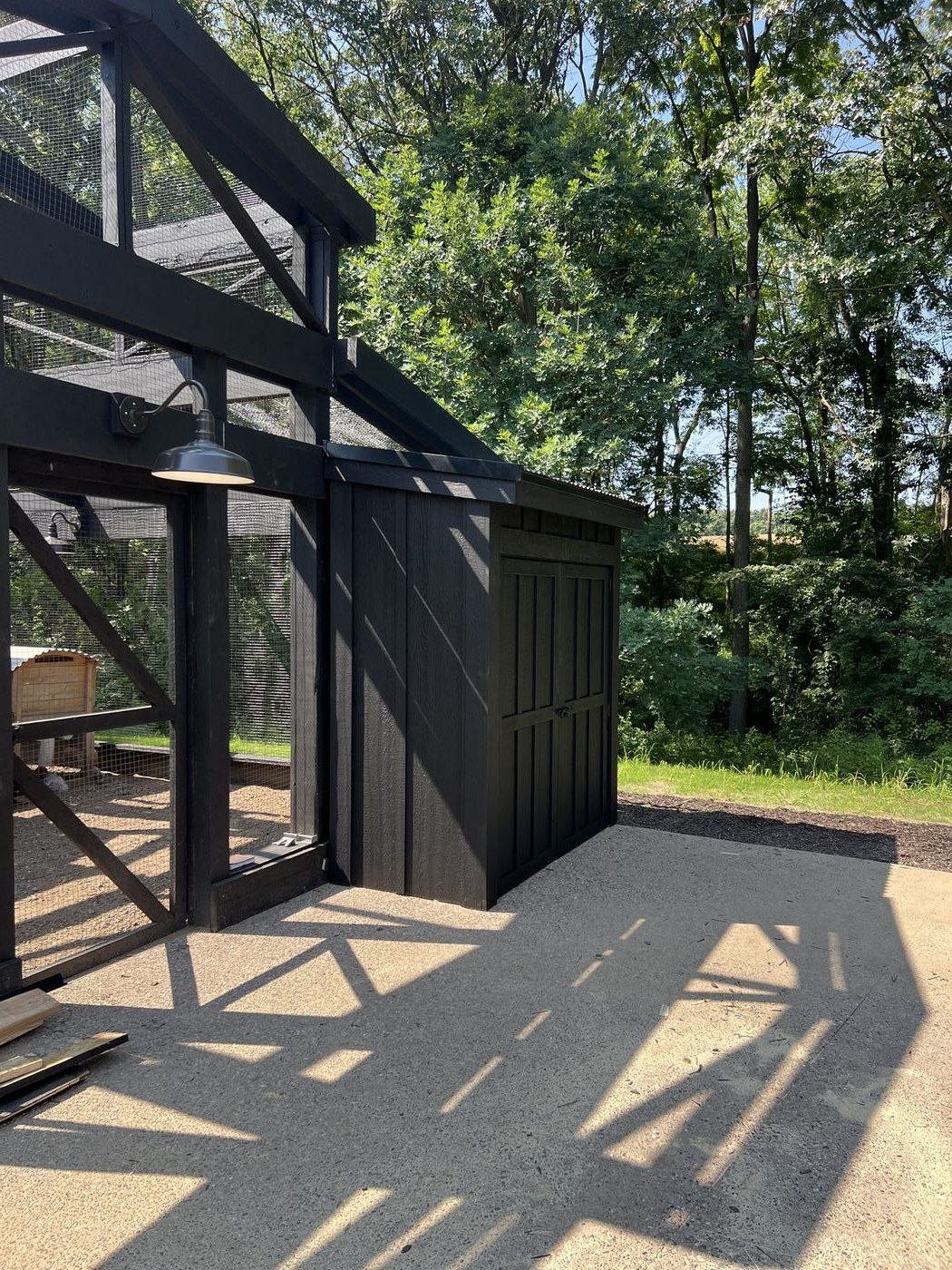 Corner detail of coop framing with board-and-batten storage shed and gooseneck barn light